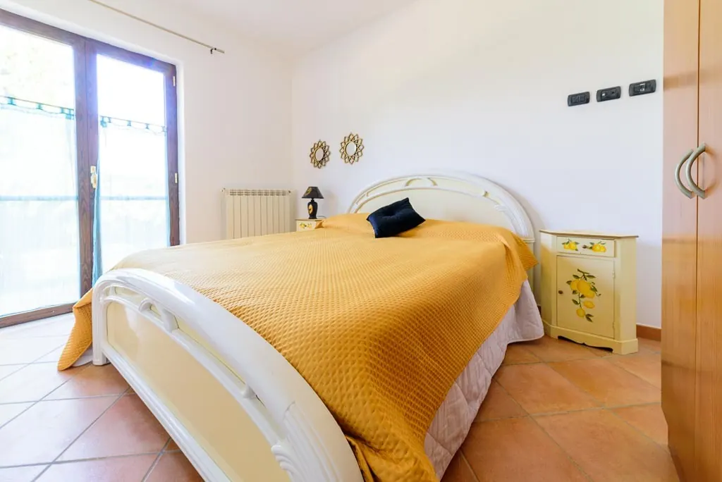 Bright bedroom: double room at Villa MaLuGio with yellow bedspread and French door to the balcony, Casal Velino