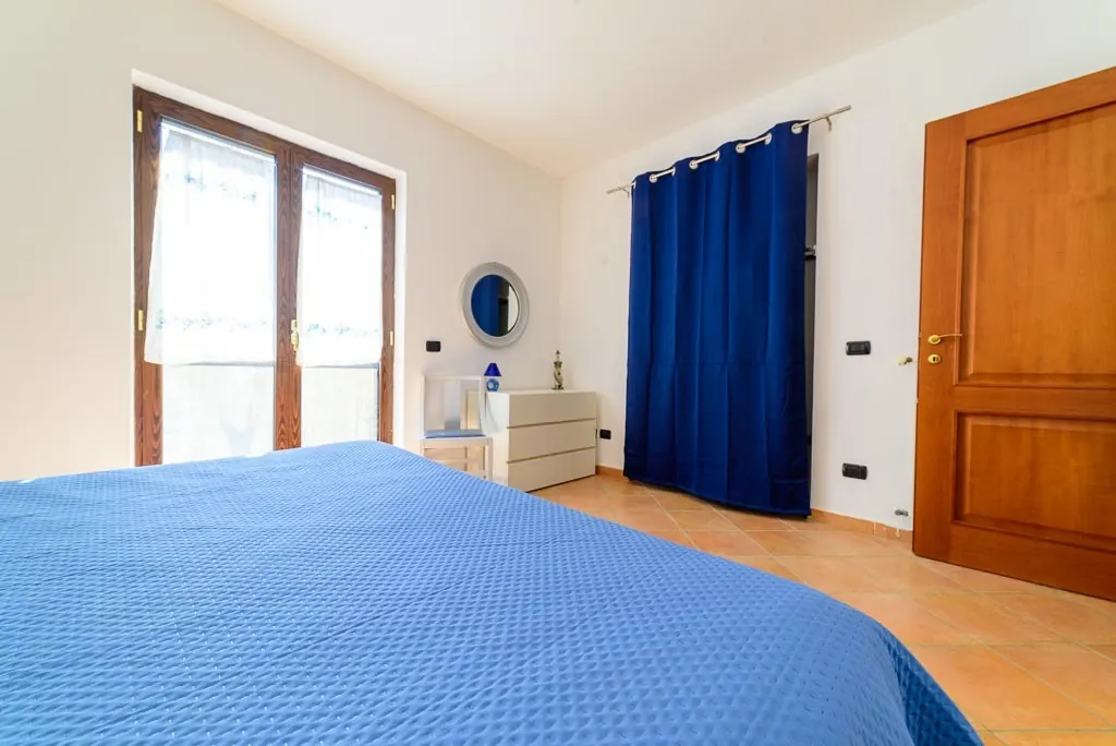 Garden Room with balcony: double room at Villa MaLuGio with blue bedspread, blue curtain and balcony over Cilento, Casal Velino