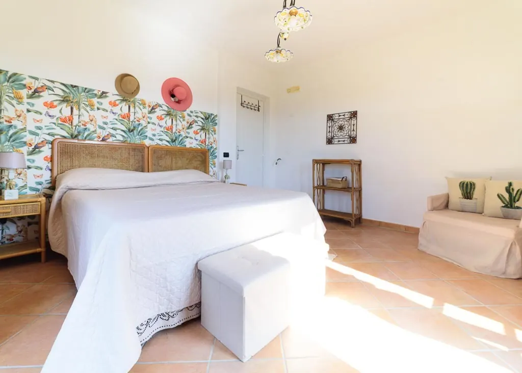 Botanical bedroom: double room at Villa MaLuGio with rattan headboard, botanical wallpaper and small sofa, Casal Velino
