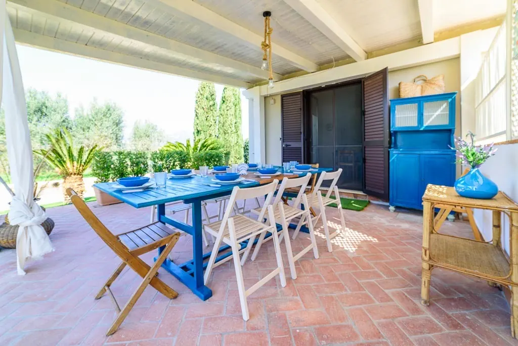 Dining under the portico: portico of Villa MaLuGio with blue table set for 12 guests, Cilento olive trees and cypresses