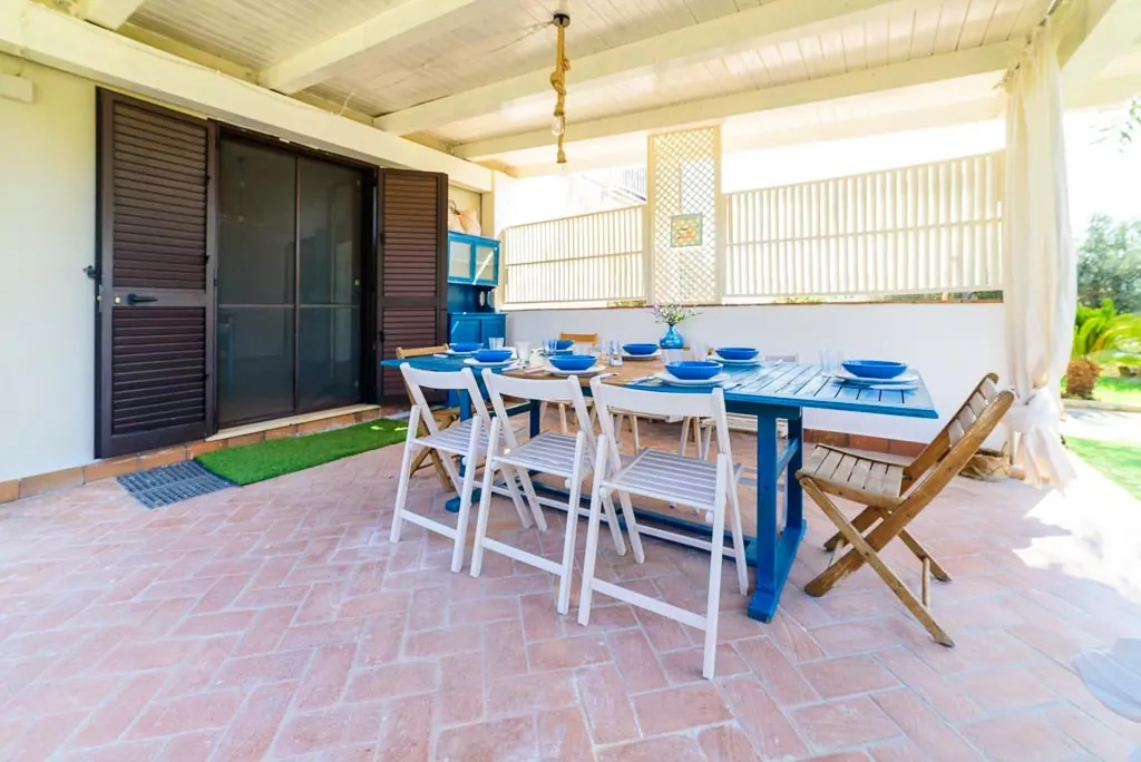 Dining on the veranda: terracotta veranda of Villa MaLuGio with blue table and folding chairs, Casal Velino